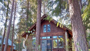A cabin with a wooden exterior, large windows, and a porch with benches. - Crazy Squirrels Cabin at Timberline Meadows (Winthrop)