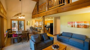 A spacious living area with a dining table, two sofas, and a wooden coffee table. A kitchen is visible in the background. - Crazy Squirrels Cabin at Timberline Meadows (Winthrop)