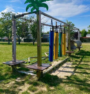 Ein Spielplatz im Freien mit Klettergerüst, Schaukeln und Rutsche.