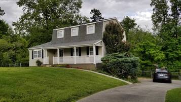 A two-story house with a front porch, a driveway, and a car parked in the driveway.