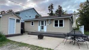 A two-story house with a covered patio area featuring a table and chairs.
