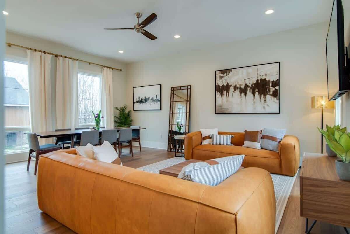 A modern living room with a sofa set, dining area, and artwork on the walls.