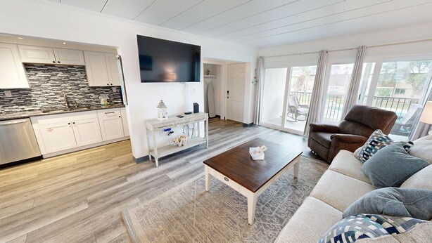 Ett modernt vardagsrum med en soffa, ett soffbord och en tv som är monterad på väggen.
