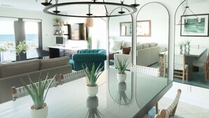 Una sala de estar moderna con una mesa de comedor de vidrio, sofás y vistas al océano.