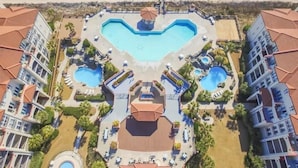 Un resort con una piscina central con forma de corazón, rodeada de varias piscinas más pequeñas y un pabellón central.