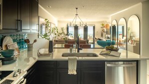 Una cocina moderna con una isla central, electrodomésticos de acero inoxidable y vistas al salón.
