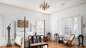 A four-poster bed with a bench, a rocking chair, and a small table in a room with wooden floors and white walls. - Beautiful historic home in Newport (Middletown)