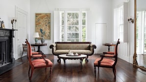 A room with a sofa, two chairs, a round table, a fireplace, and a large mirror. - Beautiful historic home in Newport (Middletown)