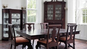 A dining room with a large wooden table, six chairs, a chandelier, and a glass cabinet with china. - Beautiful historic home in Newport (Middletown)