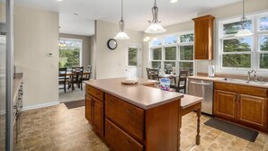 Una cocina amplia con una isla grande, armarios de madera e iluminación colgante.