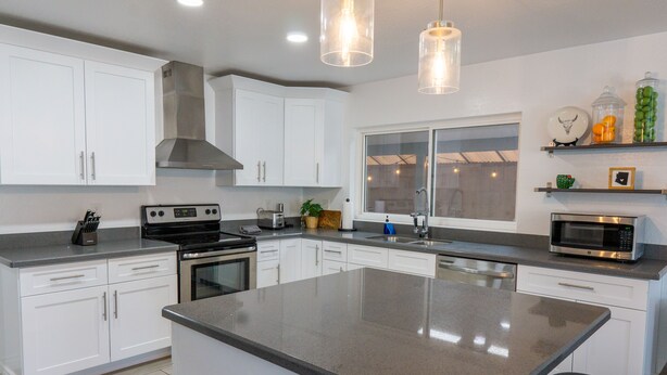 A modern kitchen with white cabinets, stainless steel appliances, and a large island. - Prickly Pear Desert Oasis- 3 Bedroom/Pool/Spa/Putting Green (Glendale)