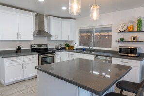 A modern kitchen with white cabinets, stainless steel appliances, and a large island. - Prickly Pear Desert Oasis- 3 Bedroom/Pool/Spa/Putting Green (Glendale)