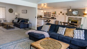 A modern living room with a dark blue sofa, a glass coffee table, and a patterned rug. - Prickly Pear Desert Oasis- 3 Bedroom/Pool/Spa/Putting Green (Glendale)