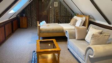 A cozy attic bedroom with a bed, a sofa, and a small table.