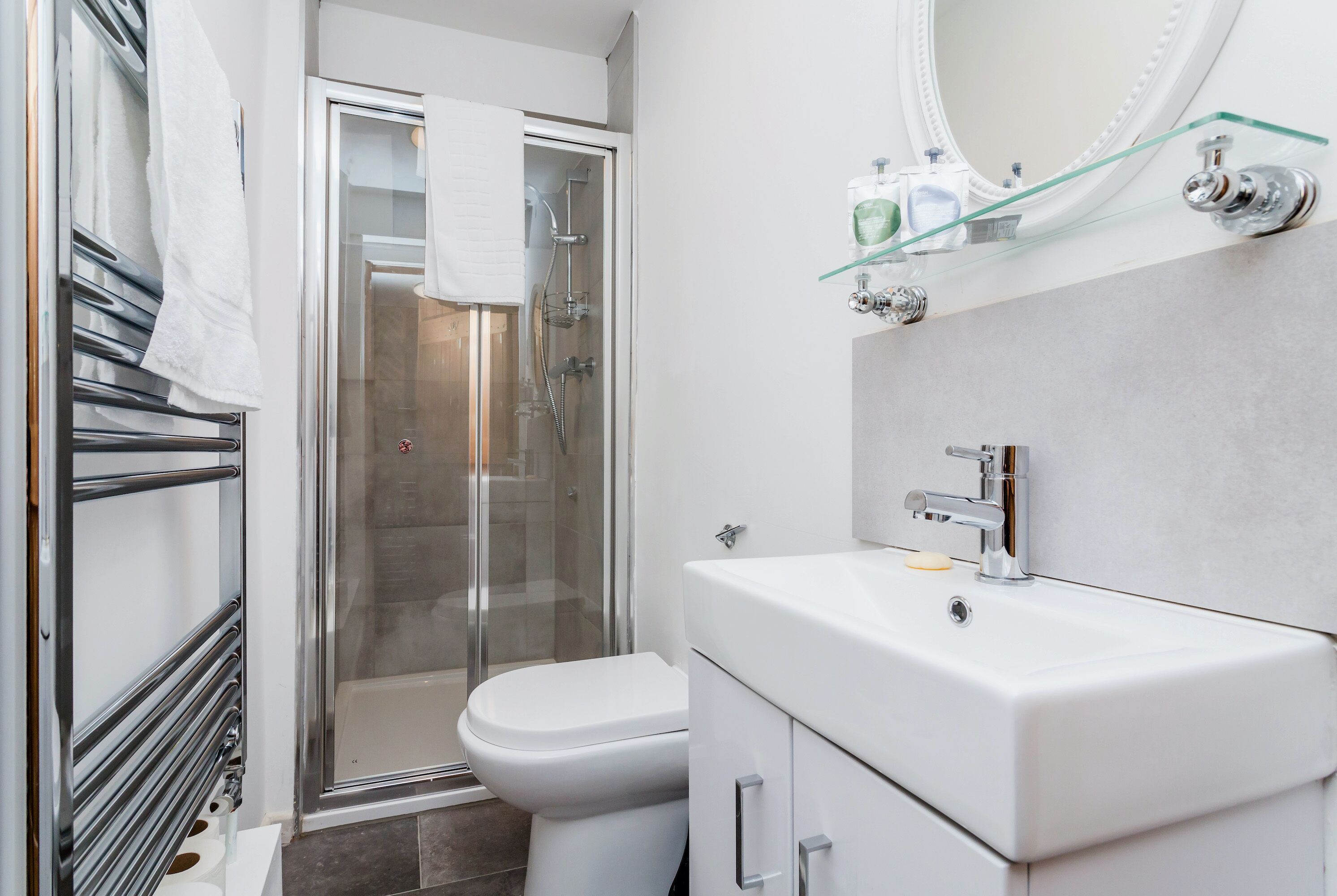 A modern bathroom with a glass shower enclosure, a white sink, and a toilet.