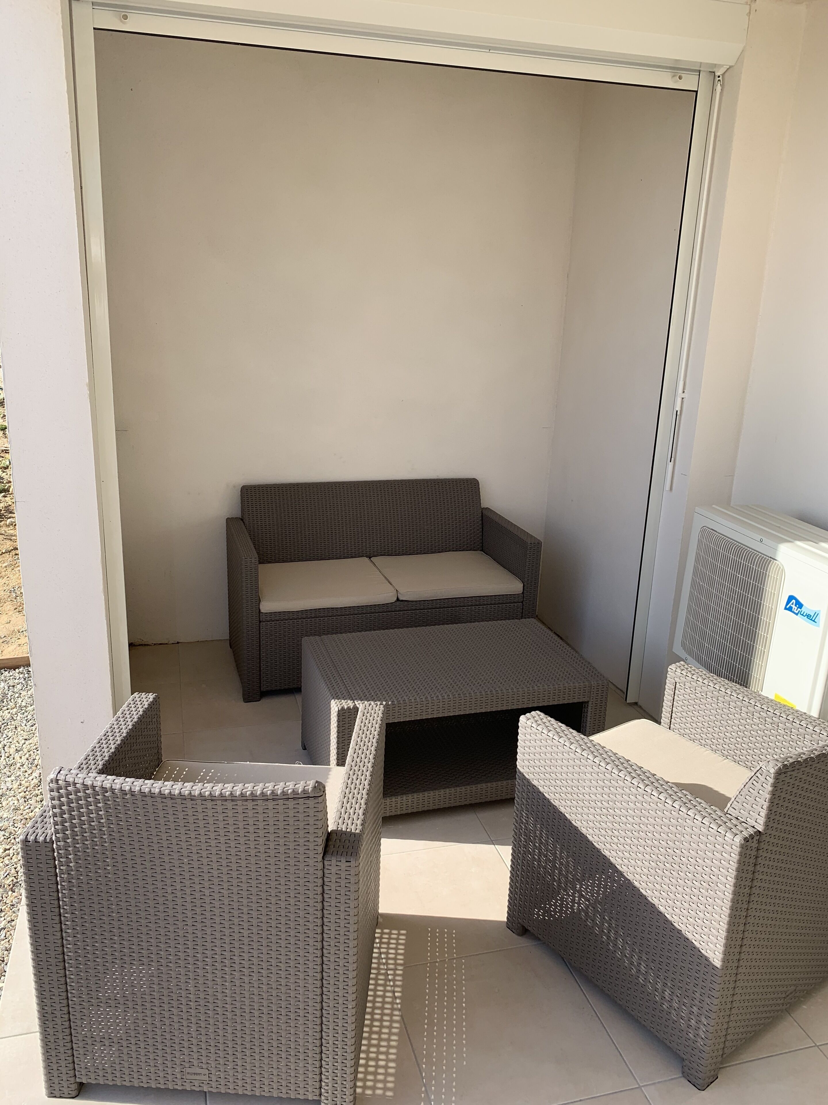 Un espace patio aménagé avec un canapé, deux fauteuils et une petite table.