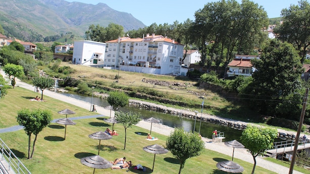 Ein Hotel am Flussufer mit Außenbestuhlung und Flussblick.