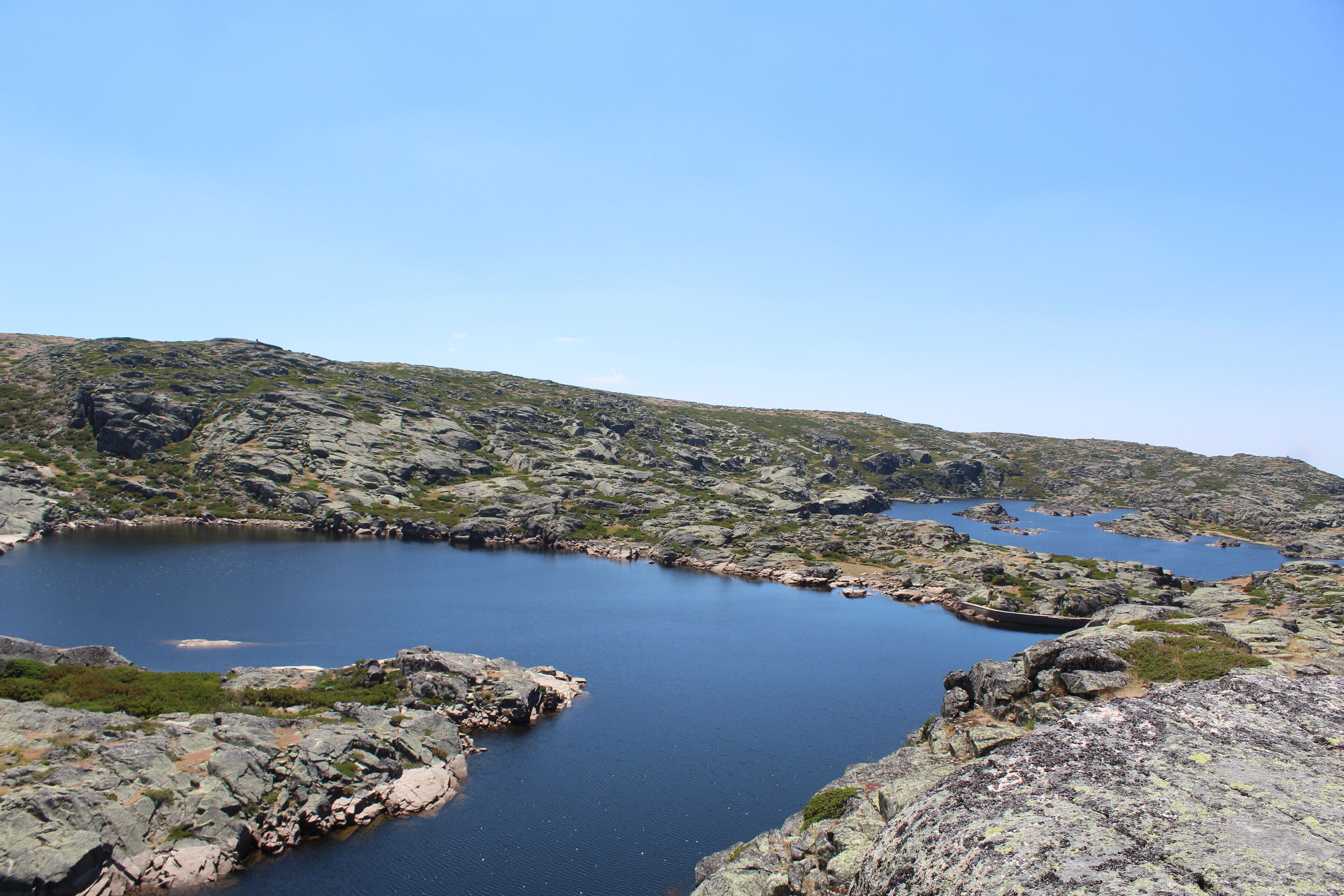A rocky landscape with a calm lake surrounded by hills.