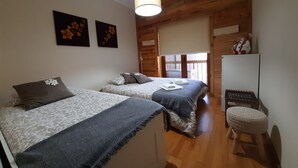 Een gezellige slaapkamer met twee bedden, een houten plafond en een klein houten krukje.