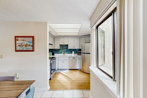 Kitchen with skylight and large window offering a view of the outdoors.