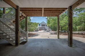 A covered outdoor area with a wooden staircase leading to a house. - Fitz Us Fine: Spacious, Adorable Beach Home in Family-friendly Neighborhood (Oak Island)