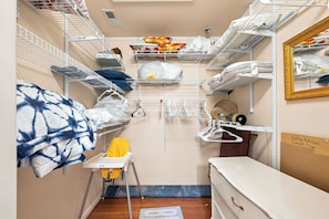 A compact storage room with metal shelves, a mirror, and a small chair.