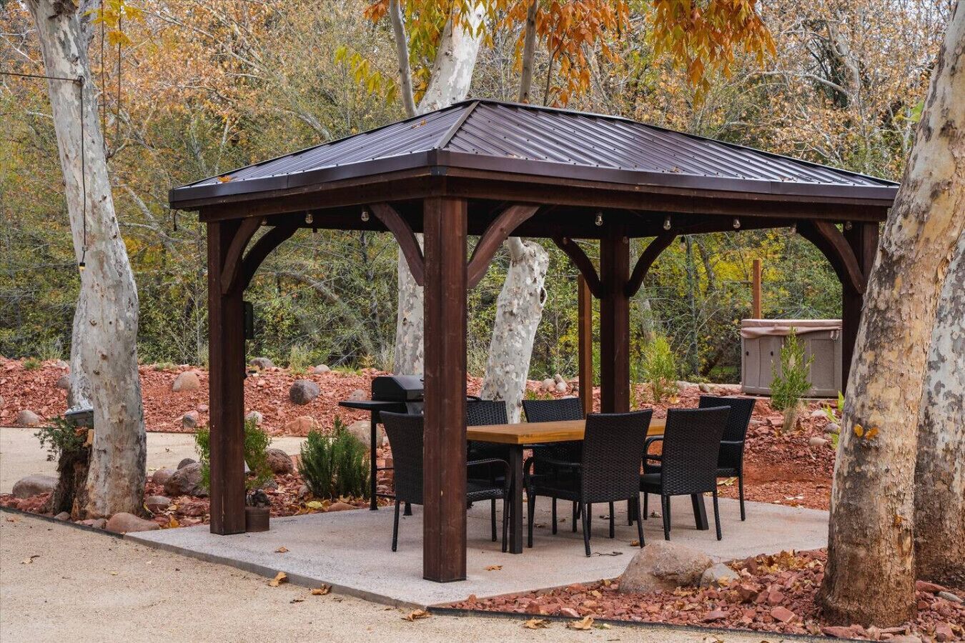 A gazebo with a wooden roof and a table with chairs underneath.