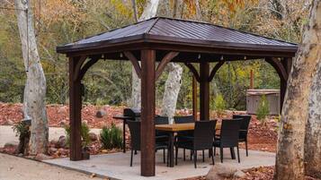 A gazebo with a wooden roof and a table with chairs underneath.