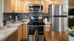 A kitchen with wooden cabinets, a stainless steel refrigerator, a microwave, a stove, and a sink. - 19 Creekside Retreat (Sedona)