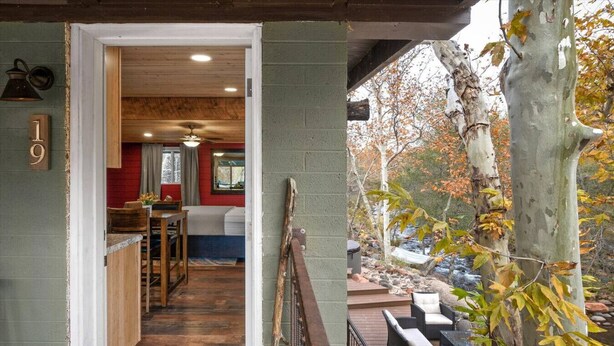 A wooden interior with a kitchen area, a dining space, and a view of a tree-lined outdoor deck. - 19 Creekside Retreat (Sedona)