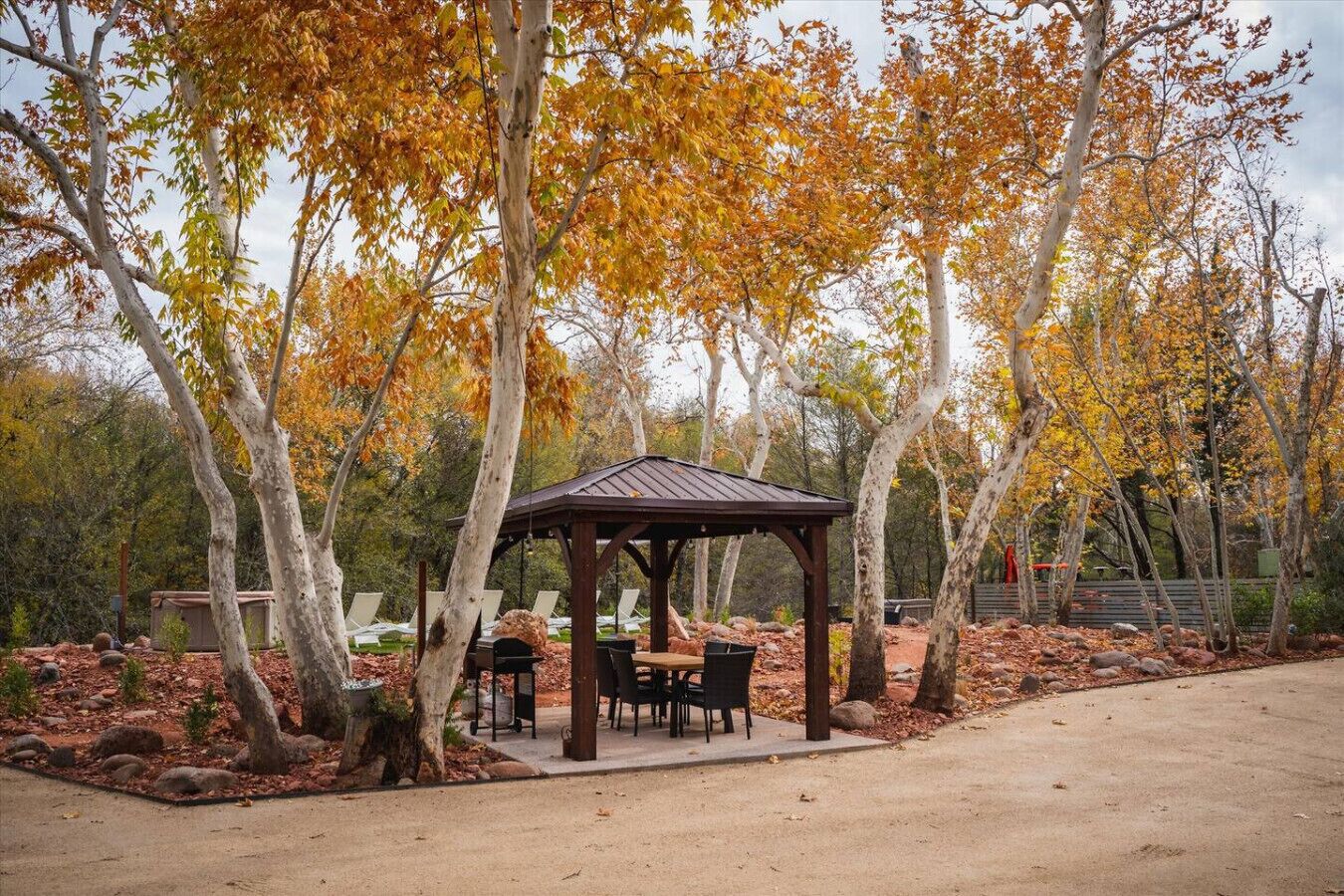 Ein Gazebo mit Außenbestuhlung, umgeben von Bäumen mit Herbstlaub.