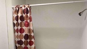 Ein Badezimmer mit Toilette, einer Badewanne und einer Duschvorhang mit Punkten.