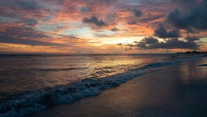 Ein Strand bei Sonnenuntergang, mit Wellen.