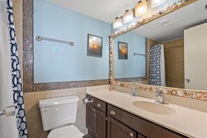 Un baño con inodoro, lavabo, tocador y espejo con marco decorativo.