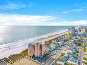 A coastal town with beachfront hotels, a beach, and a clear sky.