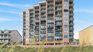 Un edificio residencial de varios pisos con balcones, ventanas grandes y techo plano.