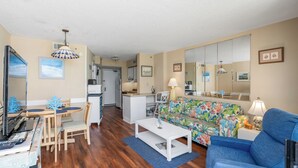 Ein kompakter Wohnraum mit einer Küchenzeile, einem Essbereich und einer Couch.