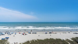 Ein weiter Sandstrand mit Sonnenschirmen und Badegästen.