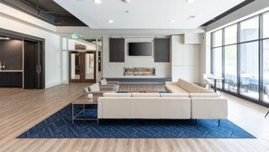Eine moderne Lobby mit einer großen Couch, einem Kamin und einem Fernsehbildschirm.
