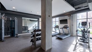 Ein modernes Fitnessstudio mit Laufbändern, Gewehrgestellen und einem großen Spiegel.