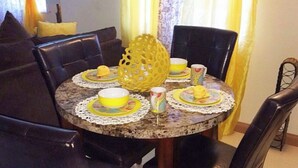 Un comedor con una mesa redonda preparada para cuatro personas, rodeada de sillas negras.