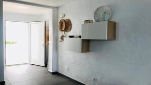 Un corridoio con una porta bianca, uno scaffale a parete con oggetti decorativi e un muro strutturato.