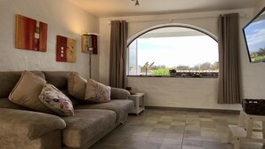 A living room with a sofa, a lamp, and a large window with curtains. - Welooveyou Lyra starlight B24 (Costa Calma (incl. Urbanización Cañada del Río))