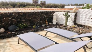 A patio with two lounge chairs, a stone wall, and a cactus. - Welooveyou Scorpius Starlight B34 (Costa Calma (incl. Urbanización Cañada del Río))