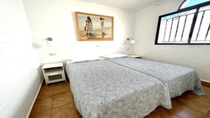 A bedroom with a bed, a nightstand, a painting, and a window with bars. - Welooveyou Scorpius Starlight B34 (Costa Calma (incl. Urbanización Cañada del Río))