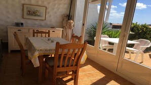 Un coin repas comprenant une table et des chaises, un meuble blanc et une fenêtre donnant sur un paysage verdoyant.