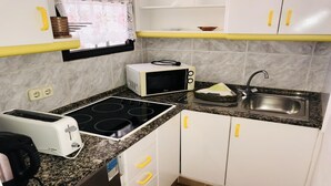 Eine kompakte Küche mit Herd, Mikrowelle, Spüle und Toaster.