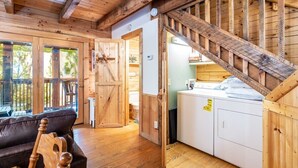A wooden interior with a staircase, a sofa, and a washing machine.