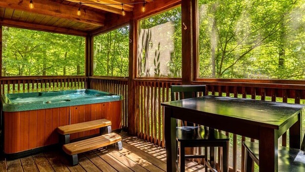 A wooden deck with a hot tub, wooden benches, and a table.