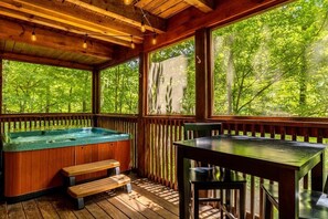 Une terrasse en bois avec un jacuzzi, des bancs en bois et une table.